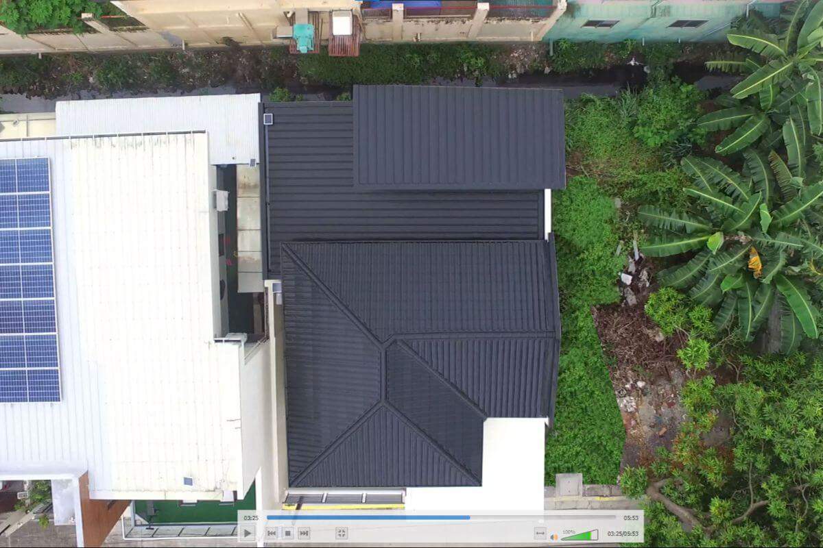 Aerial view of a dark insulated roof panel system on a residential property surrounded by greenery