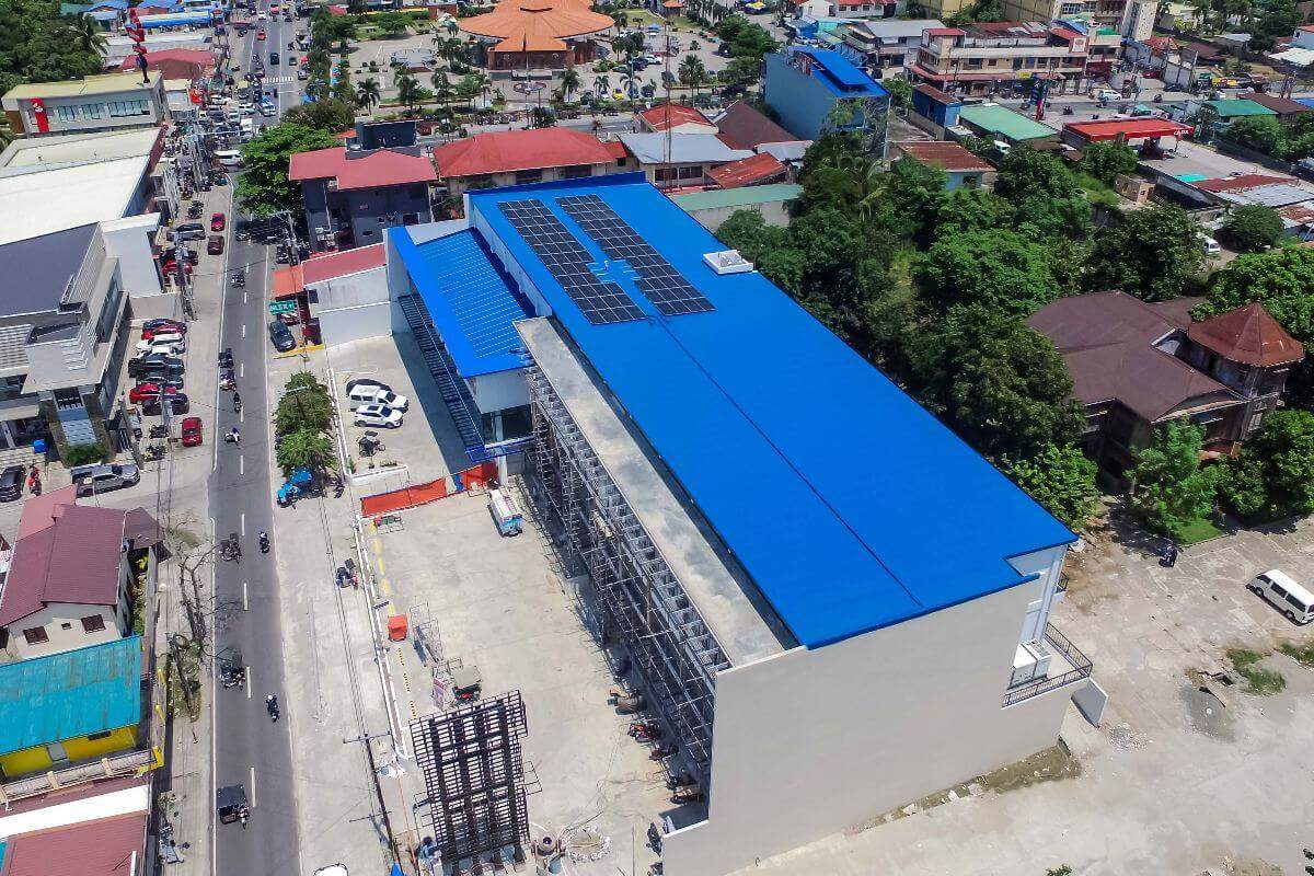 Aerial view of a commercial building with a blue insulated roof and solar panels