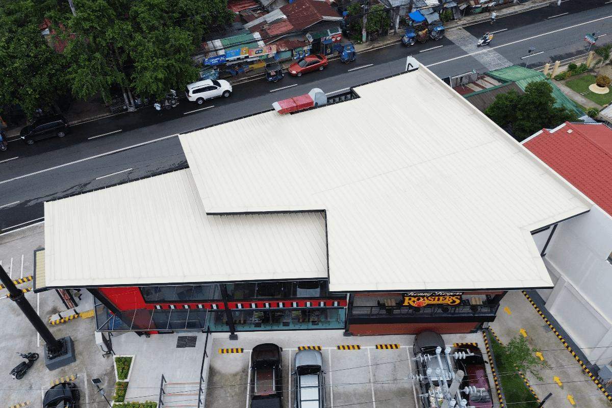 METLNK-0626A-FEAT Aerial view of a commercial building with a light-colored insulated roof beside a main road